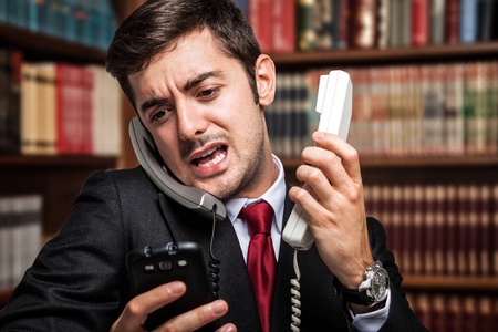 stressed businessman talking on many phones at once