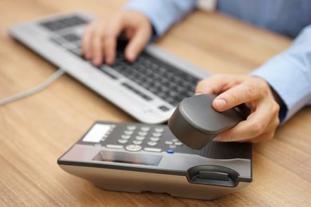 businessman hand picking up telephone receiver on business workplace